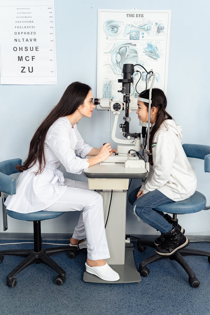 An optometrist performing an eye examination on a young girl in a clinic setting.