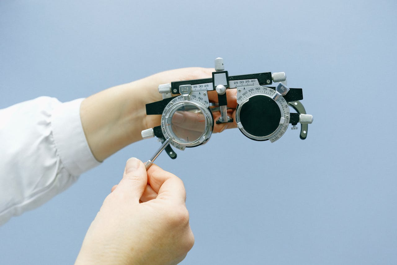 Hands adjusting an optometry trial lens set with a blue background. Ideal for vision and health topics.